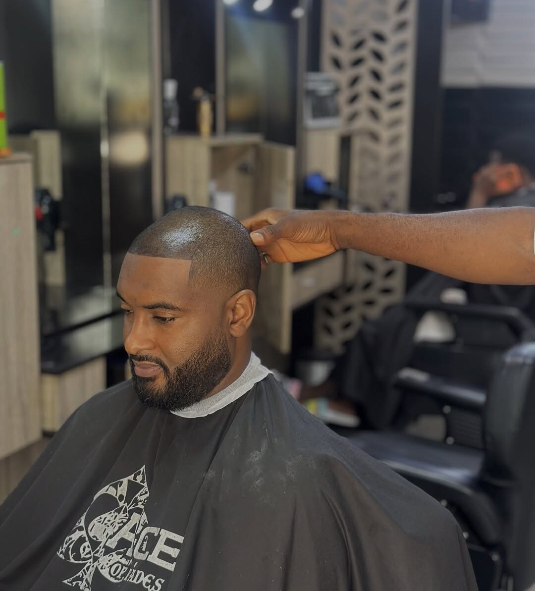 A barber's hand checking a client's line-up after a bald fade