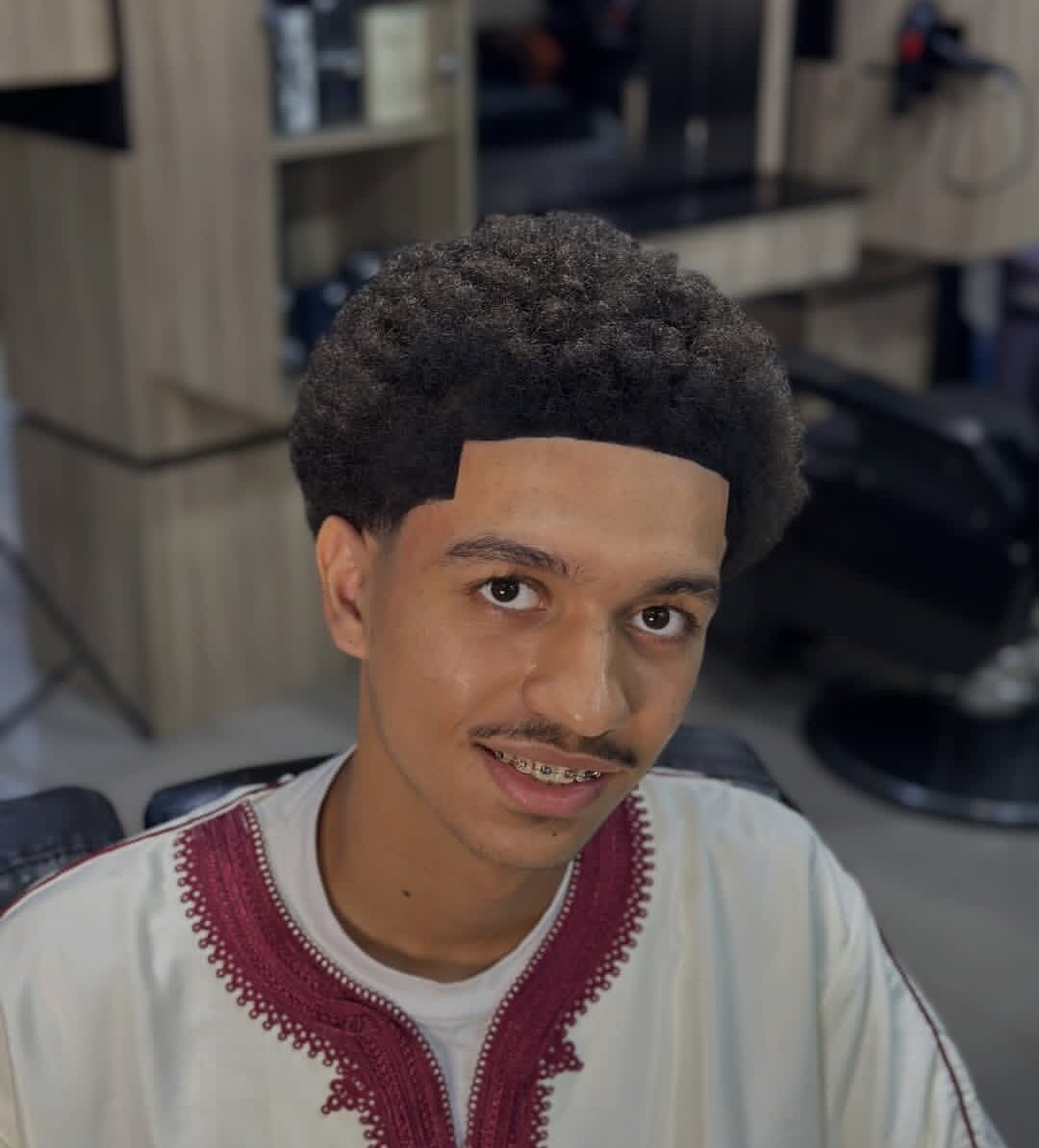 Young man with a curly top, a low taper and a squared-off hairline